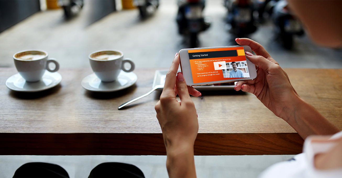 Photograph of a person watching an instructional video on their phone while sitting at a coffee shop.